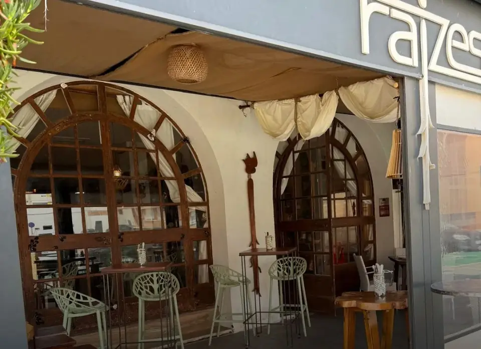 La terraza de Raizes bajo el toldo, junto a los ventanales en arco