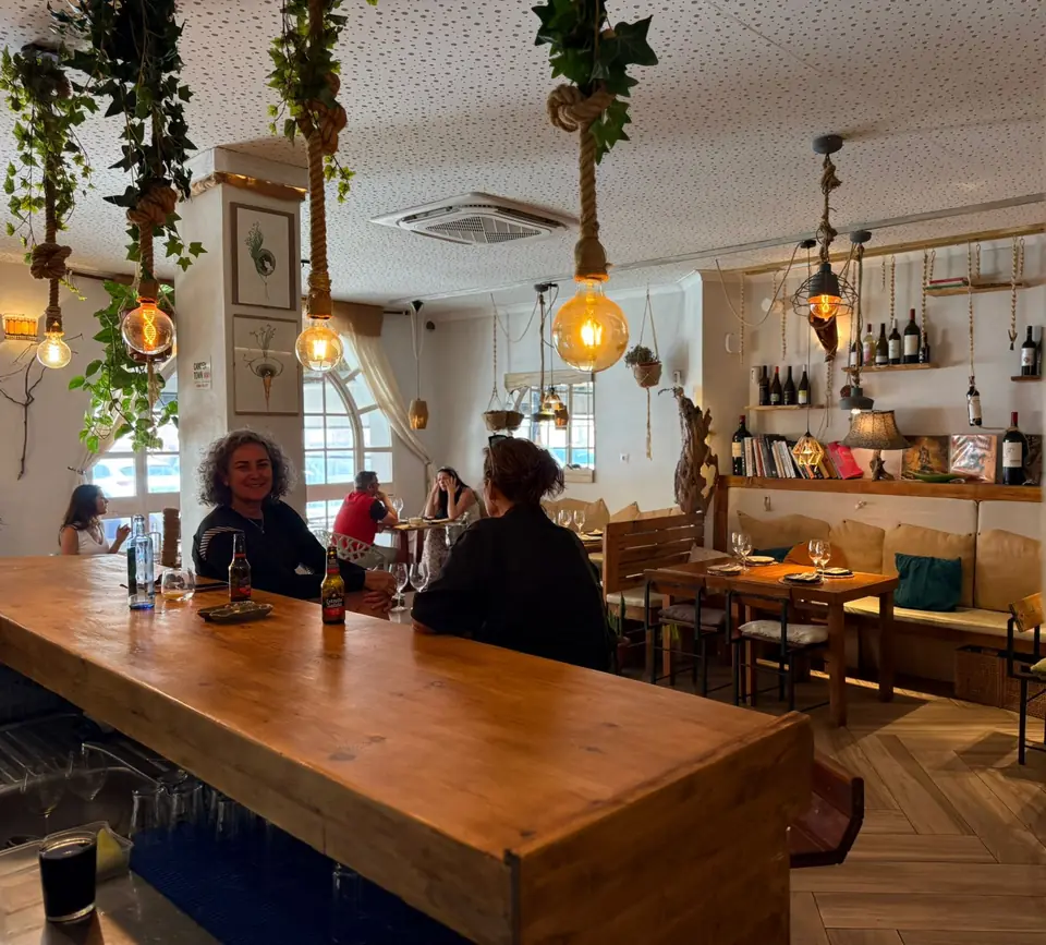 La barra de madera de Raizes con clientes cenando y el salón al fondo