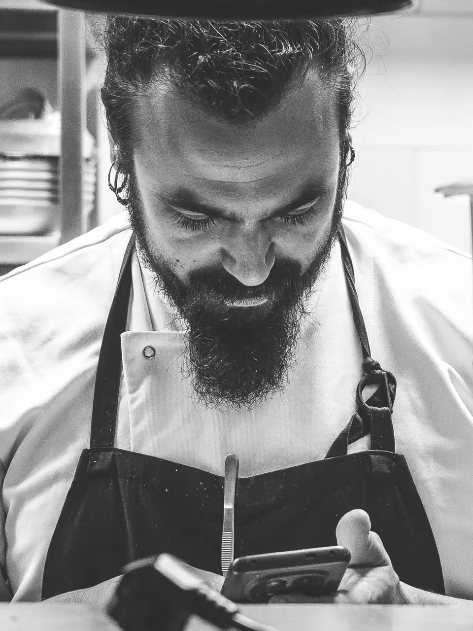 Retrato en blanco y negro de un cocinero de Raizes emplatando en el pase